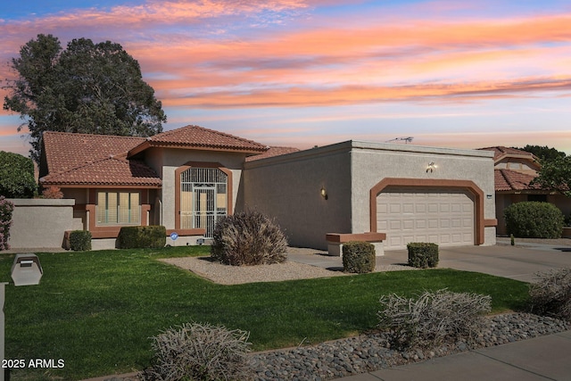 mediterranean / spanish-style home with a lawn, an attached garage, and stucco siding