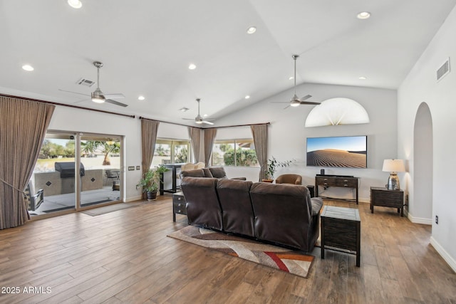 living area featuring arched walkways, wood finished floors, and visible vents