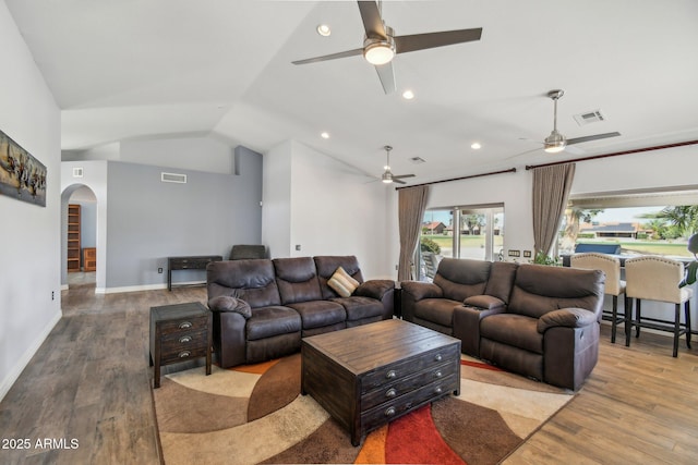 living room featuring arched walkways, visible vents, lofted ceiling, and wood finished floors