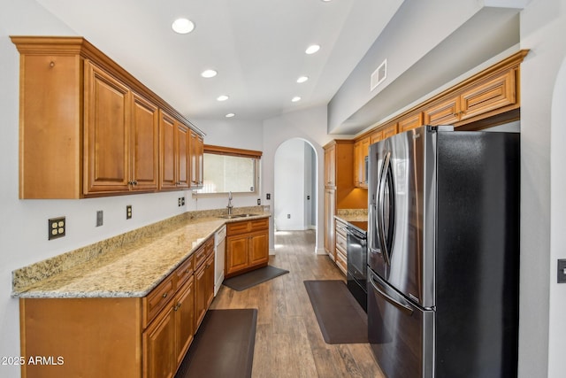 kitchen featuring stainless steel fridge, visible vents, arched walkways, white dishwasher, and a sink