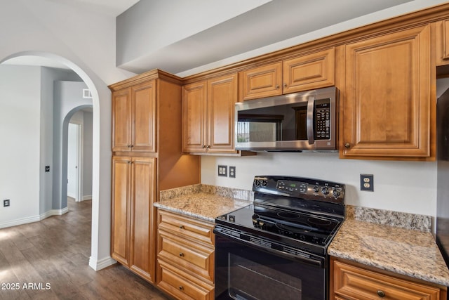 kitchen with dark wood-type flooring, black range with electric stovetop, stainless steel microwave, and light stone counters