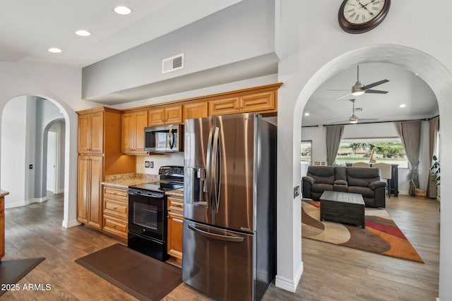 kitchen featuring dark wood-style floors, arched walkways, visible vents, appliances with stainless steel finishes, and baseboards