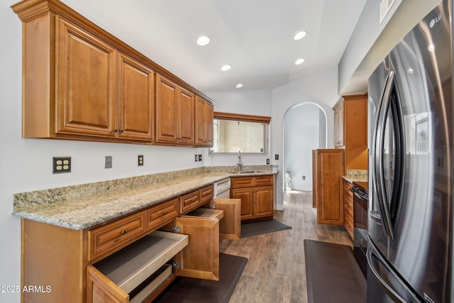 kitchen with arched walkways, dishwasher, wood finished floors, freestanding refrigerator, and a sink