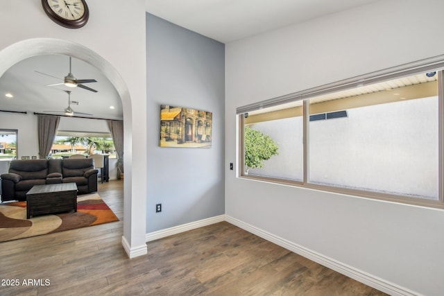 interior space with arched walkways, recessed lighting, wood finished floors, a ceiling fan, and baseboards