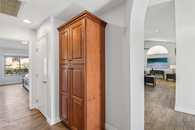 hallway with baseboards, wood finished floors, visible vents, and recessed lighting