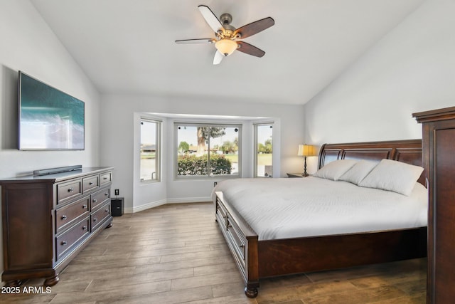 bedroom with vaulted ceiling, wood finished floors, a ceiling fan, and baseboards