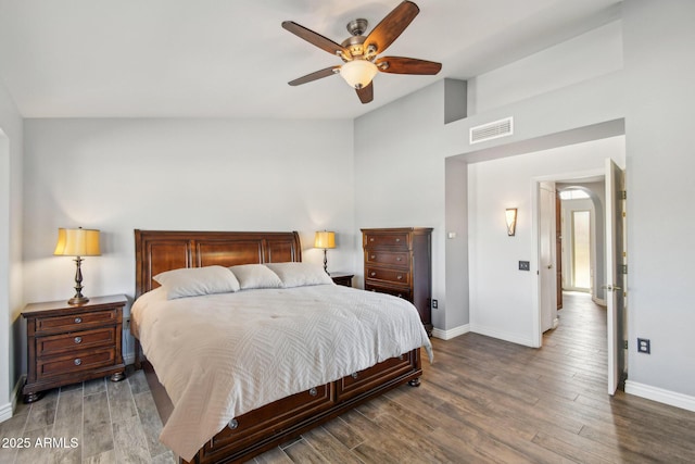 bedroom with lofted ceiling, baseboards, visible vents, and wood finished floors