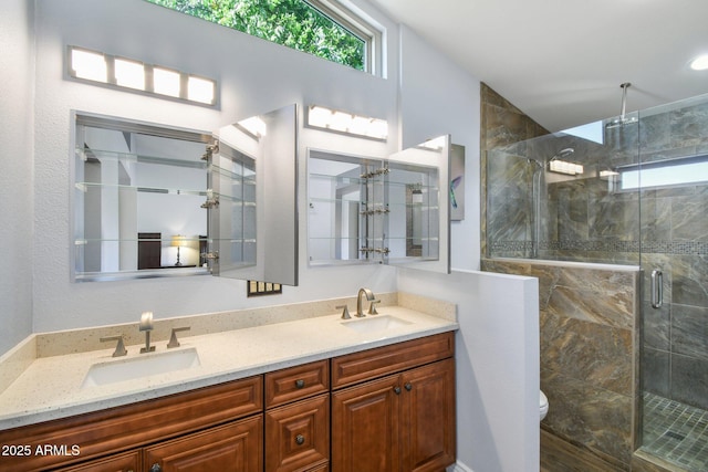 bathroom featuring a stall shower, a sink, toilet, and double vanity