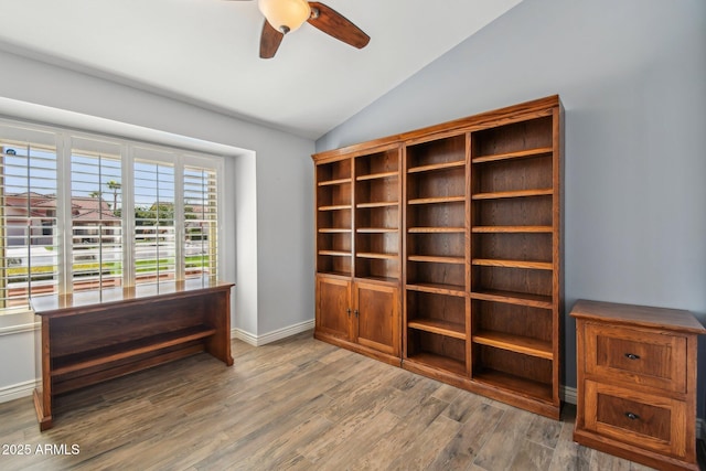 unfurnished room featuring vaulted ceiling, wood finished floors, a ceiling fan, and baseboards