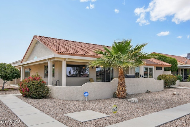 view of front of home featuring fence, a tiled roof, and stucco siding