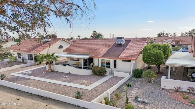 view of front of home featuring fence, a tiled roof, central AC unit, and stucco siding