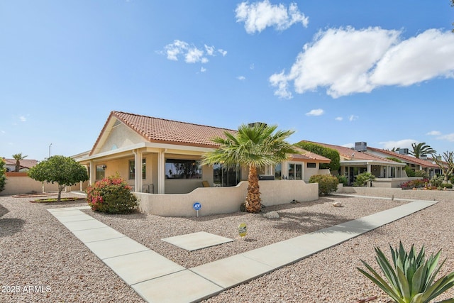 back of house featuring a tile roof and stucco siding