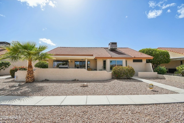 view of front facade featuring central air condition unit, fence, a tile roof, and stucco siding