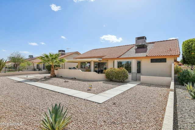 rear view of house with central air condition unit, fence, a tiled roof, and stucco siding