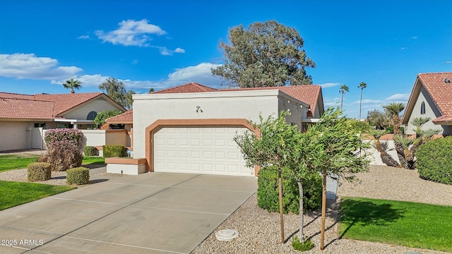 mediterranean / spanish-style home featuring concrete driveway, an attached garage, a tiled roof, and stucco siding