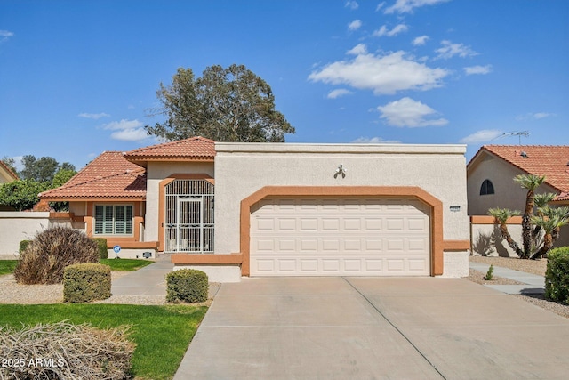 mediterranean / spanish-style house with an attached garage, a tiled roof, concrete driveway, and stucco siding