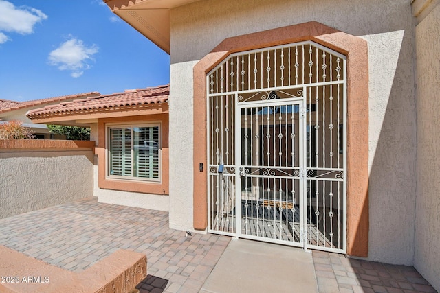 property entrance with a tiled roof and stucco siding