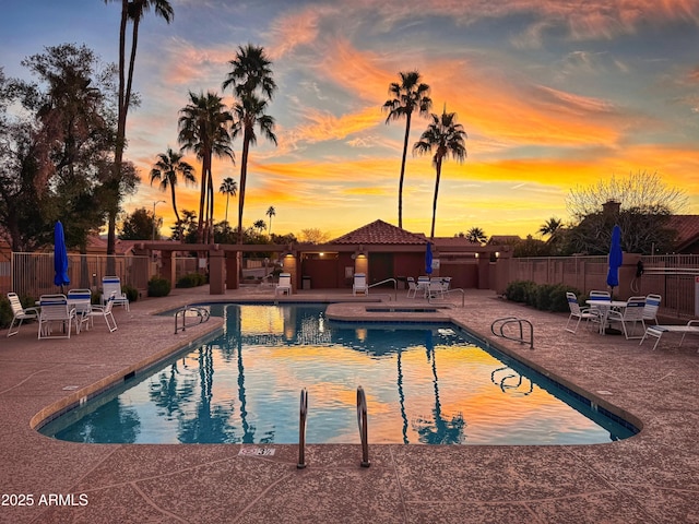 pool at dusk with a patio area