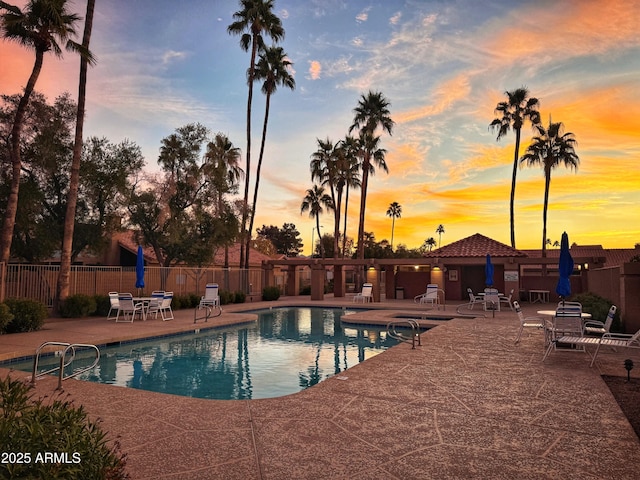 pool at dusk featuring a patio area