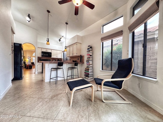 living area with ceiling fan, high vaulted ceiling, and light tile patterned floors