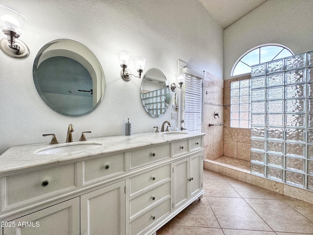 bathroom featuring vanity, vaulted ceiling, a tile shower, and tile patterned floors