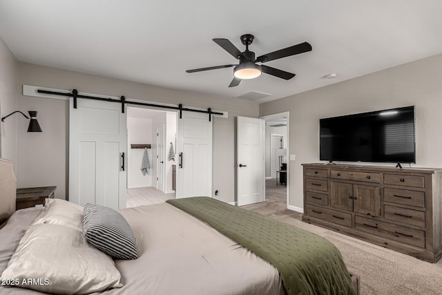 bedroom with ceiling fan, light colored carpet, ensuite bathroom, and a barn door