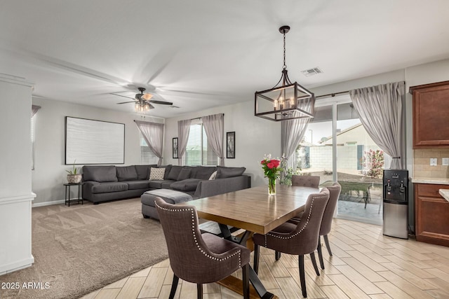 dining area with ceiling fan with notable chandelier and light hardwood / wood-style floors