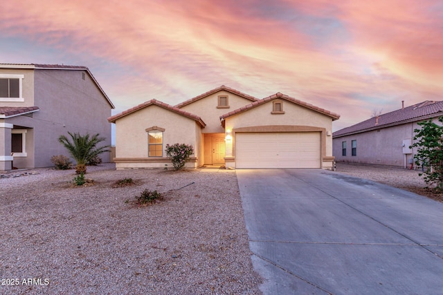 mediterranean / spanish home featuring driveway, an attached garage, a tiled roof, and stucco siding