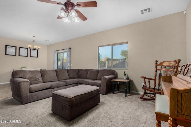 living area with ceiling fan with notable chandelier, baseboards, visible vents, and light colored carpet