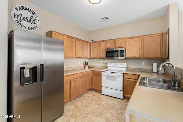 kitchen featuring appliances with stainless steel finishes, light countertops, visible vents, and a sink