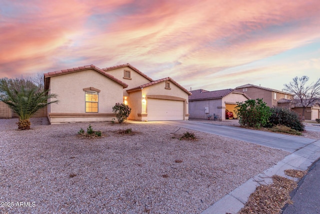 mediterranean / spanish home featuring a garage, a tiled roof, concrete driveway, and stucco siding