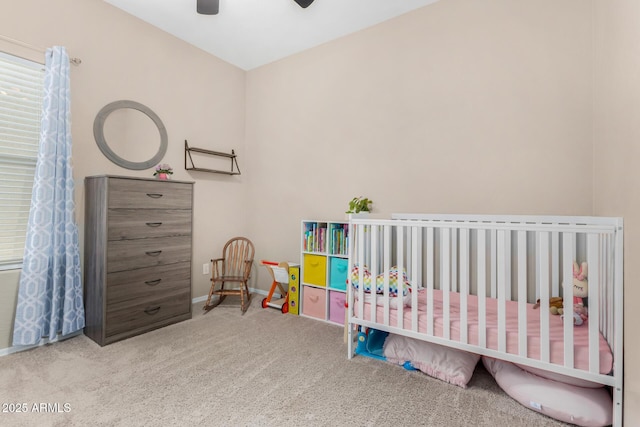 bedroom with carpet, ceiling fan, a crib, and baseboards