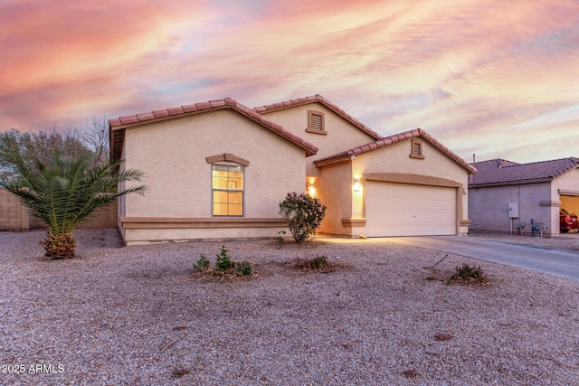 mediterranean / spanish-style home featuring a garage, a tile roof, concrete driveway, and stucco siding