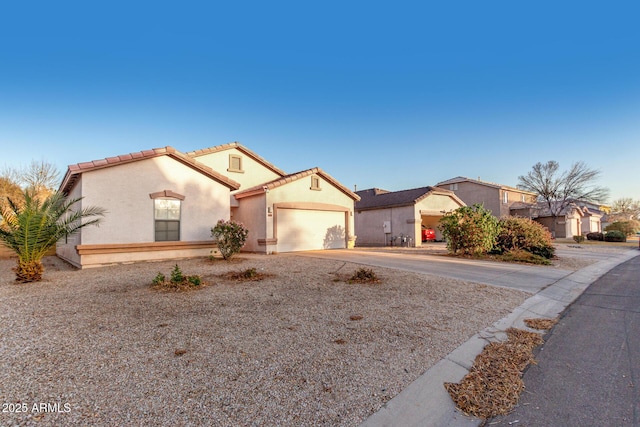 mediterranean / spanish-style house featuring a garage, a tiled roof, concrete driveway, and stucco siding