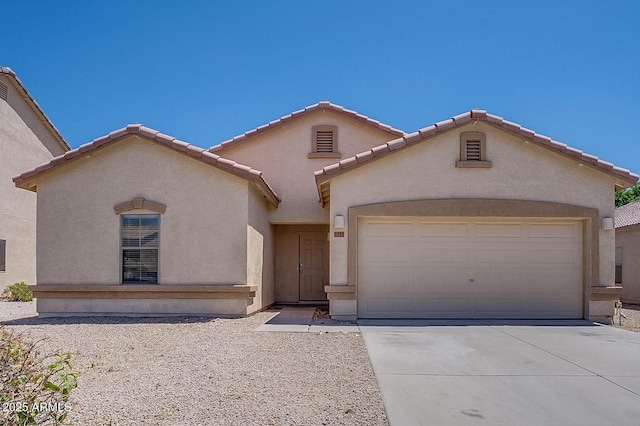 mediterranean / spanish home with driveway, a tiled roof, an attached garage, and stucco siding