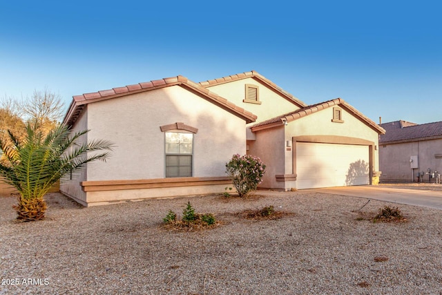 mediterranean / spanish home with a garage, concrete driveway, a tile roof, and stucco siding