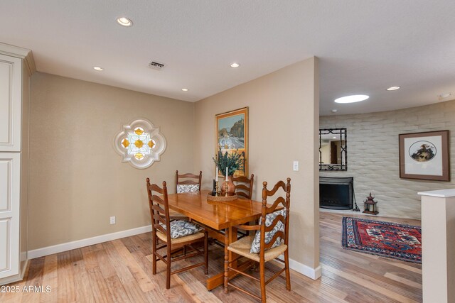 dining space featuring recessed lighting, a fireplace, light wood-style flooring, and baseboards