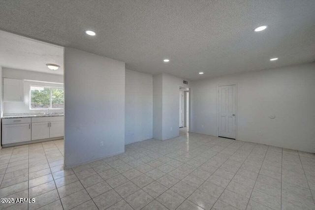 unfurnished room with a textured ceiling, recessed lighting, and a sink