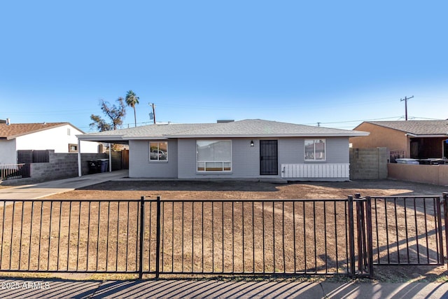 ranch-style house with a carport, a fenced front yard, and concrete driveway