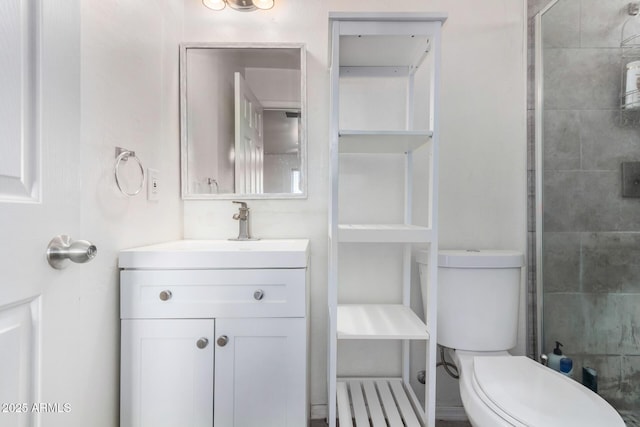 bathroom featuring vanity, a shower with shower door, and toilet