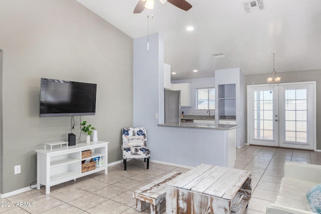 tiled living room with sink and ceiling fan with notable chandelier