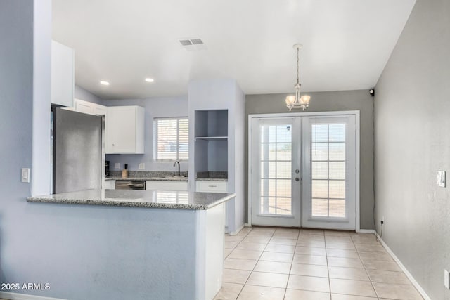 kitchen with sink, stainless steel appliances, white cabinets, decorative light fixtures, and kitchen peninsula