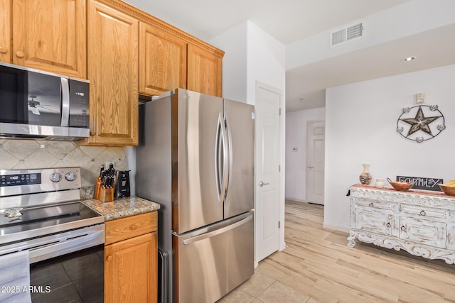 14000 N 94th St N Unit 1129, Scottsdale, AZ 85260 - kitchen with appliances with stainless steel finishes, tasteful backsplash, light wood-style flooring, and light stone counters