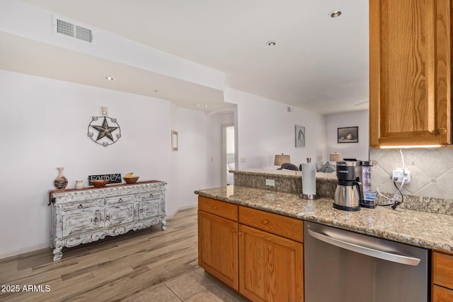 14000 N 94th St N Unit 1129, Scottsdale, AZ 85260 - kitchen featuring dishwasher, backsplash, a peninsula, light stone counters, and light wood-style floors
