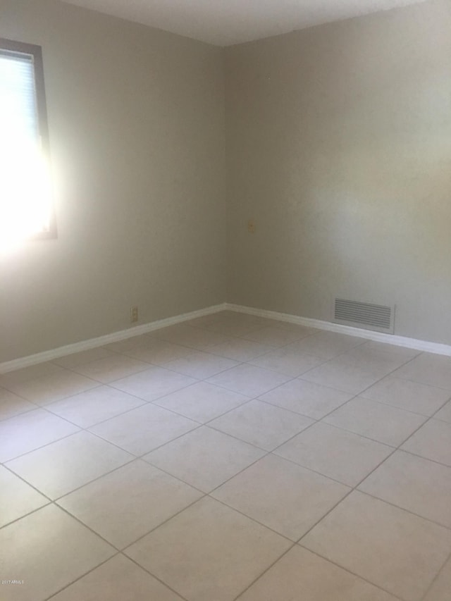 empty room with visible vents, baseboards, and light tile patterned floors