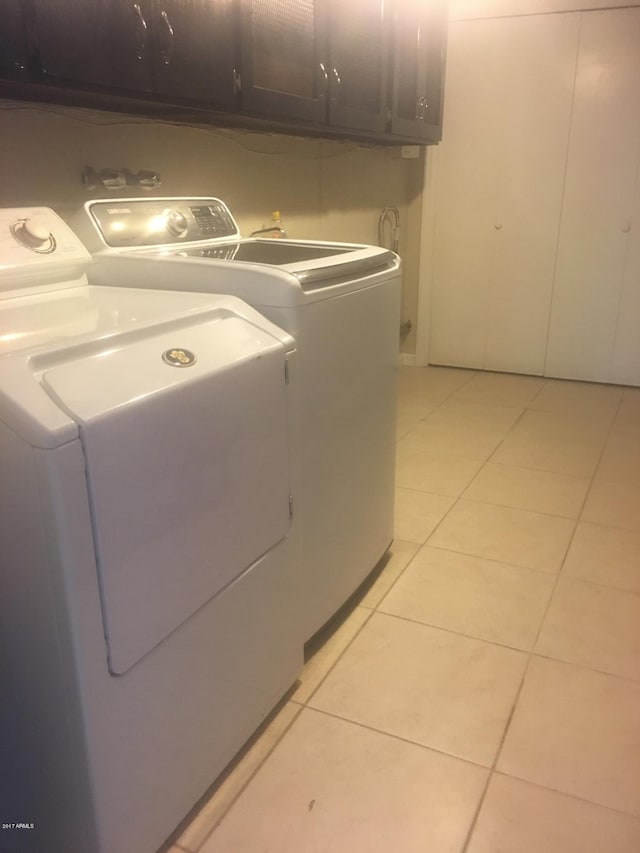 laundry room with light tile patterned flooring, washing machine and clothes dryer, and cabinet space