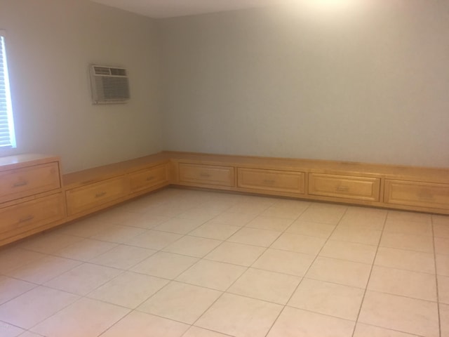 empty room with a wall mounted air conditioner and light tile patterned floors