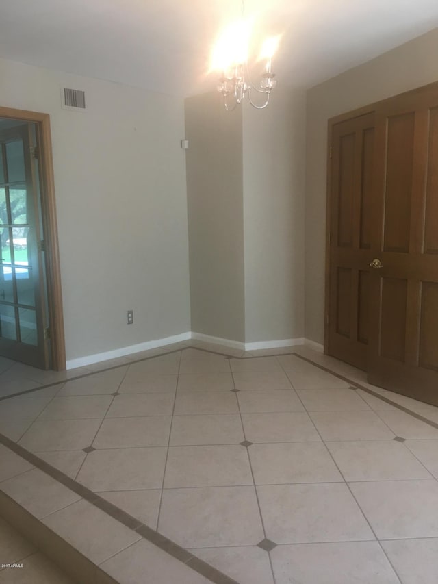 spare room with an inviting chandelier, visible vents, baseboards, and light tile patterned floors