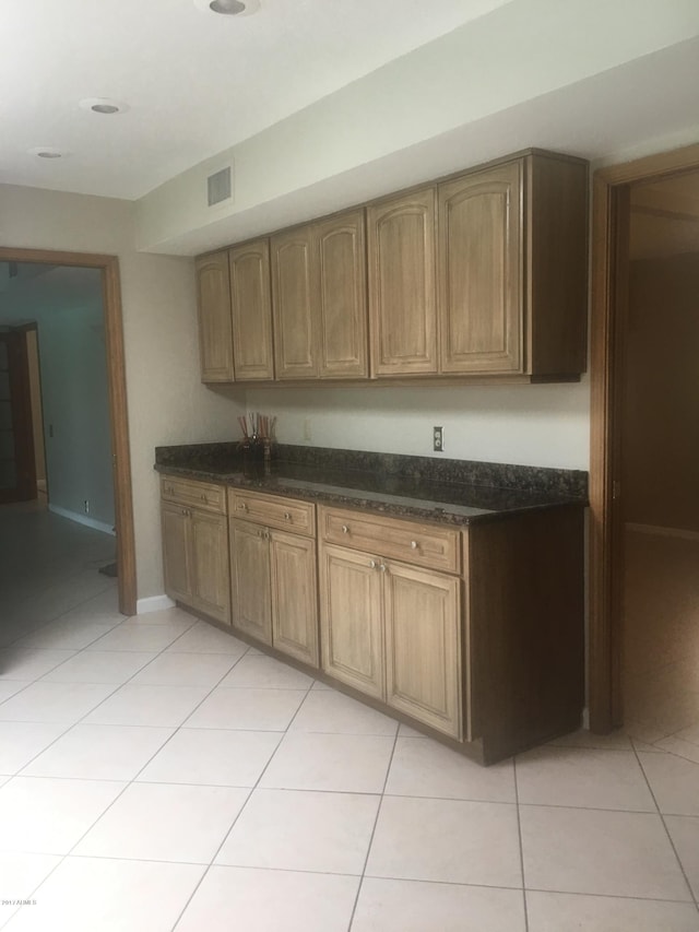 kitchen featuring brown cabinets, visible vents, baseboards, and light tile patterned floors