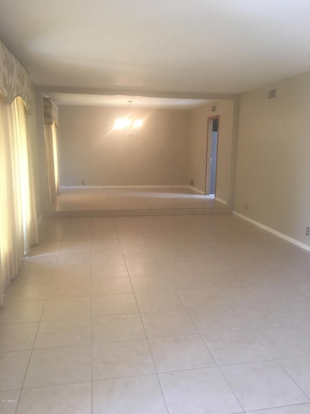 empty room featuring light tile patterned floors, visible vents, and baseboards